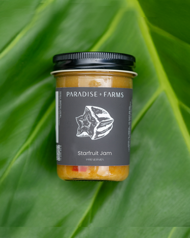 Jar of Paradise Farms starfruit jam on a green leaf background